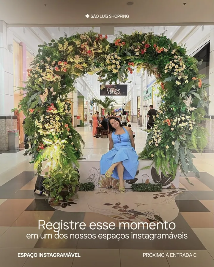 Arco floral do espaço instagramável perto da entrada C, com uma cliente sentada no banco