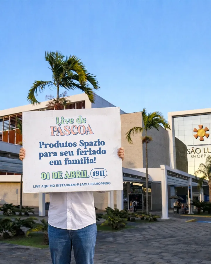 Pessoa segura uma placa da Live de Páscoa em frente à fachada do São Luís Shopping